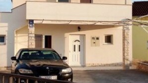 Un edificio de dos pisos con un coche estacionado adelante.