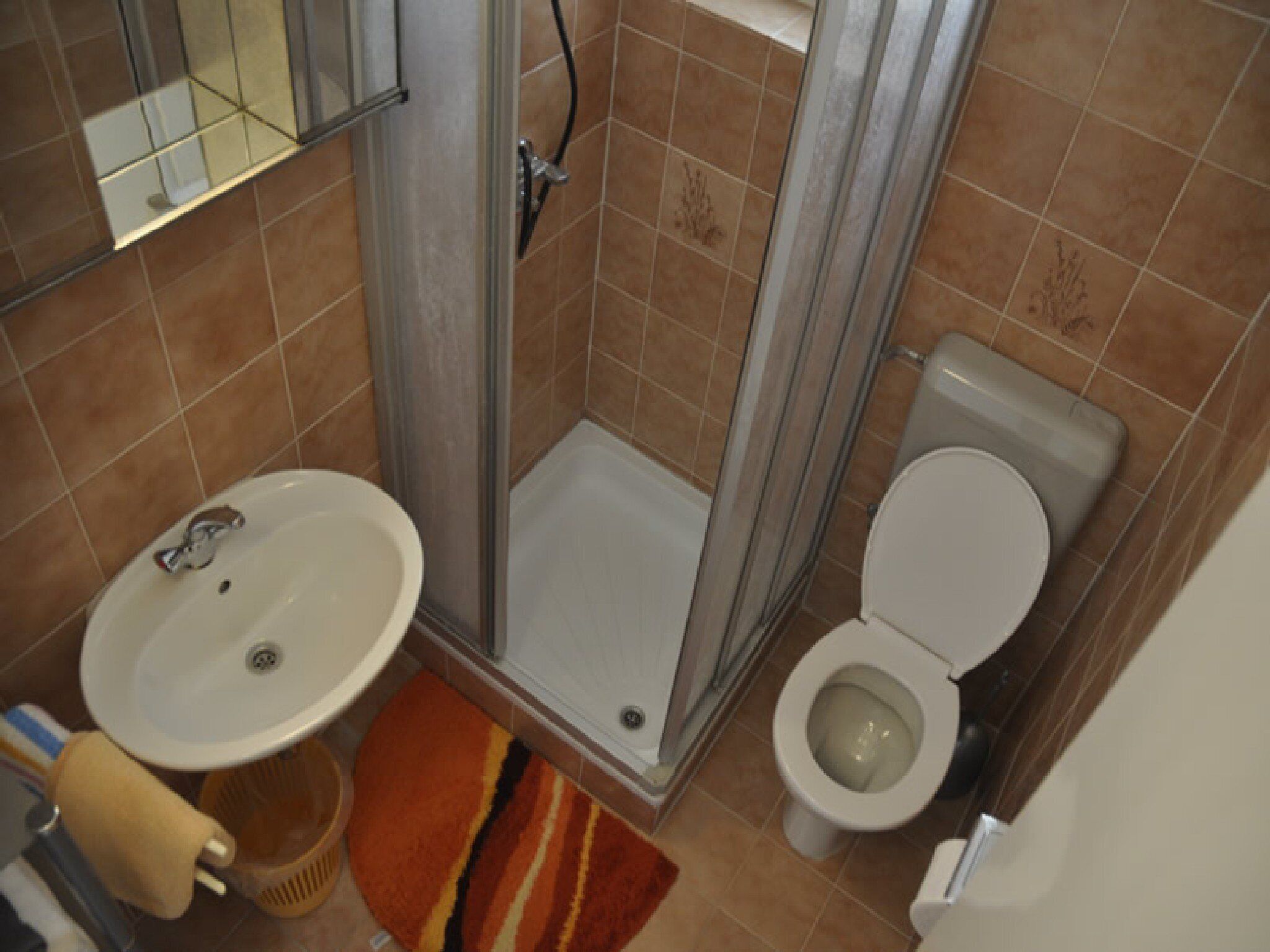 Une salle de bain équipée d’une douche, de toilettes, d’un lavabo et d’un miroir.