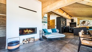Una sala de estar moderna con chimenea, un sofá con cojines azules y un comedor con sillas de madera.