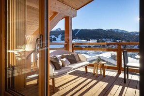 Une terrasse en bois avec un canapé et une table, offrant une vue sur un paysage montagneux enneigé.