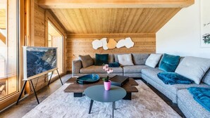 Una sala de estar moderna con techo de madera, un sofá grande, una mesa de centro y un cuadro en la pared.