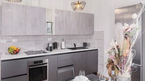 A modern kitchen with grey cabinets, a stainless steel refrigerator, and a dining area set for a meal. - Villa Tomicich (Rasa)