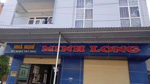 A building with a blue facade and a red sign that reads "MINH LONG". - Minh Long Guesthouse - Quang Truong (Thuc Phan)