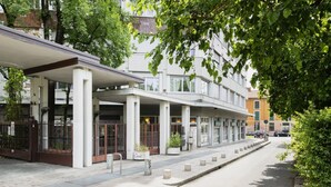 A modern building with a covered entrance, large windows, and a sidewalk with bollards. - Easylife - Residential apartment on Navigli area (Milano)