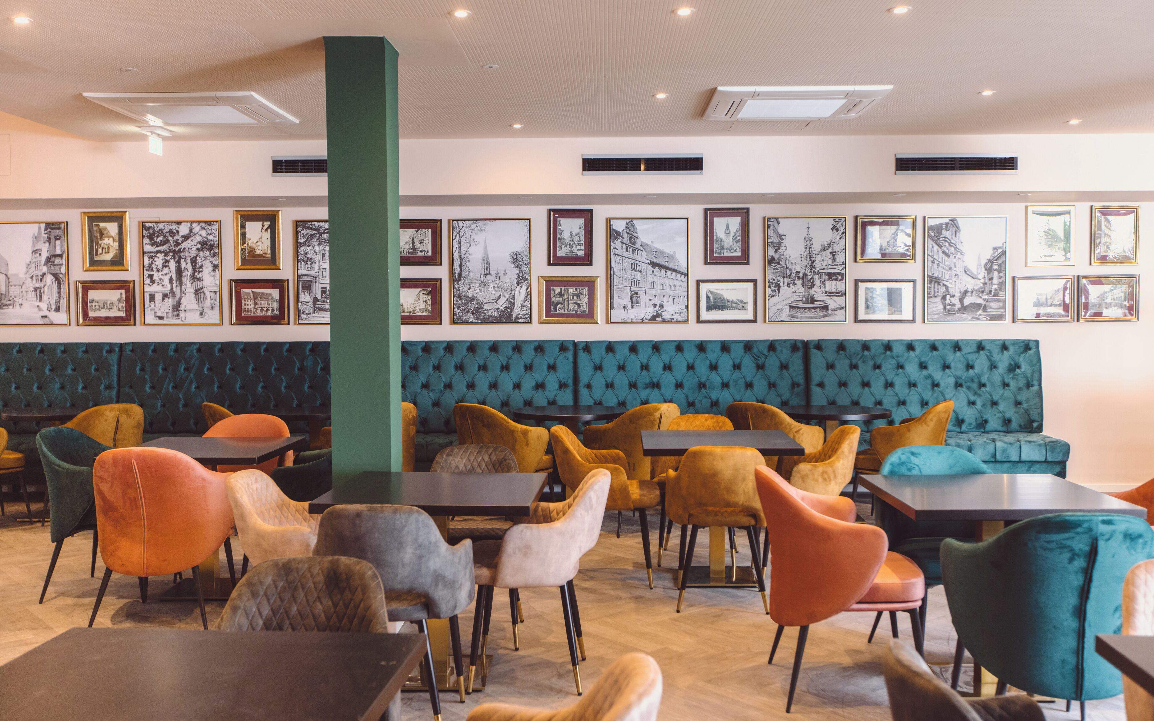A restaurant with a variety of seating options including tables and booths, framed black and white photographs on the walls, and a modern ceiling design.