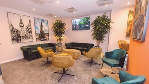 A lounge area with a green sofa, yellow chairs, and a large plant. - Hotel am Rathaus (Freiburg im Breisgau)