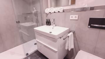 Ein modernes Badezimmer mit Duschkabine aus Glas, einem weißen Waschbecken und einer Toilette.