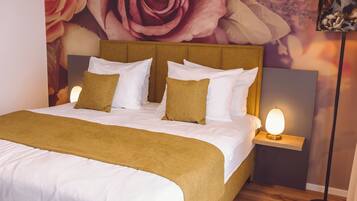 A neatly made bed with white and mustard bedding, a headboard, and two bedside lamps.
