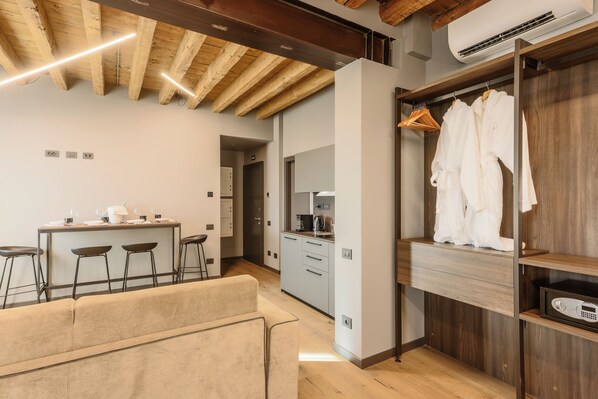 Una cocina moderna con techo de madera, un comedor con taburetes de bar y un vestidor con batas colgadas.
