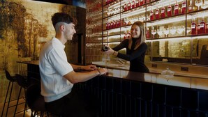 A bar with a rustic wall and shelves of bottles.