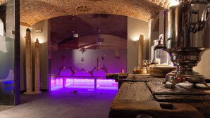 A room with a wooden ceiling, a large metal object on the right, and a purple-lit area in the background.