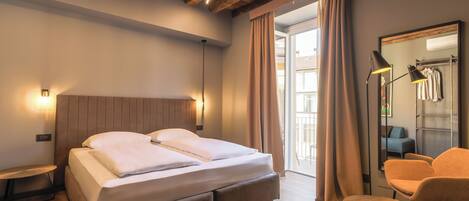 A bedroom with a wooden ceiling, a bed with white linens, a nightstand, a chair, and a mirror.