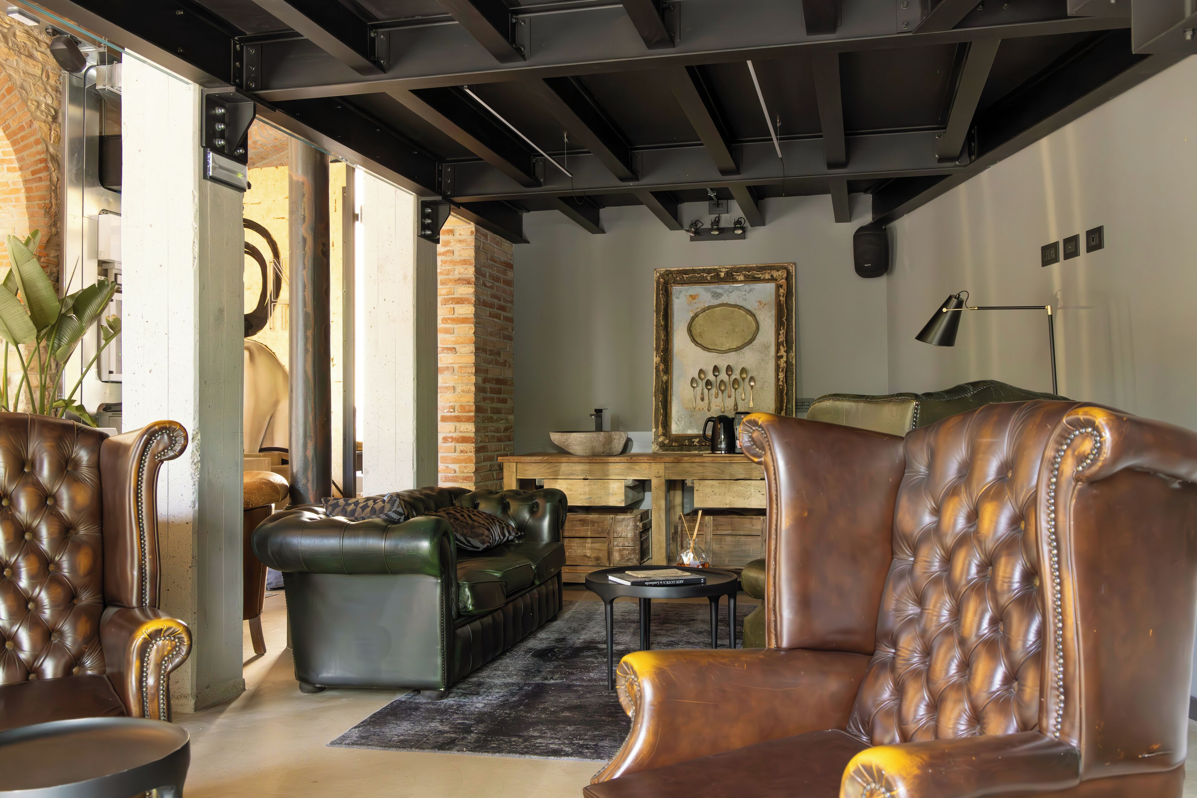 A spacious living area with leather sofas, a coffee table, and a rustic brick wall.