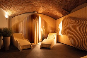 Un cuarto de spa con dos sillones reclinables, una pared de madera con listones verticales y un techo de ladrillo.