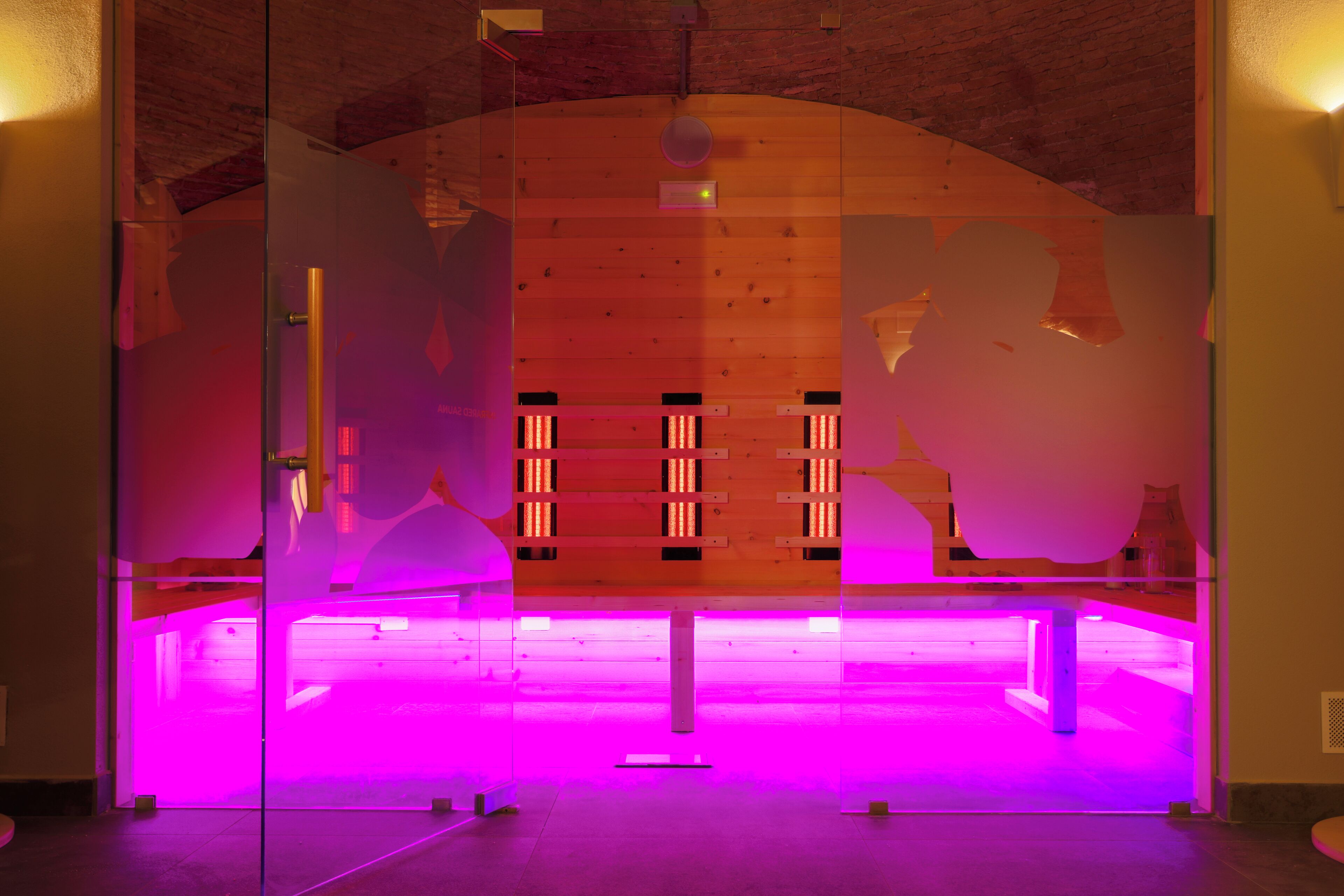 Een modern interieur met een glazen scheidingswand, houten lambrisering en een paars verlichte vloer.