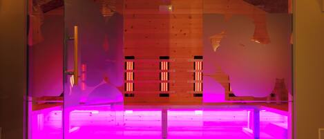 A modern interior with a glass partition, wooden paneling, and a purple-lit floor.