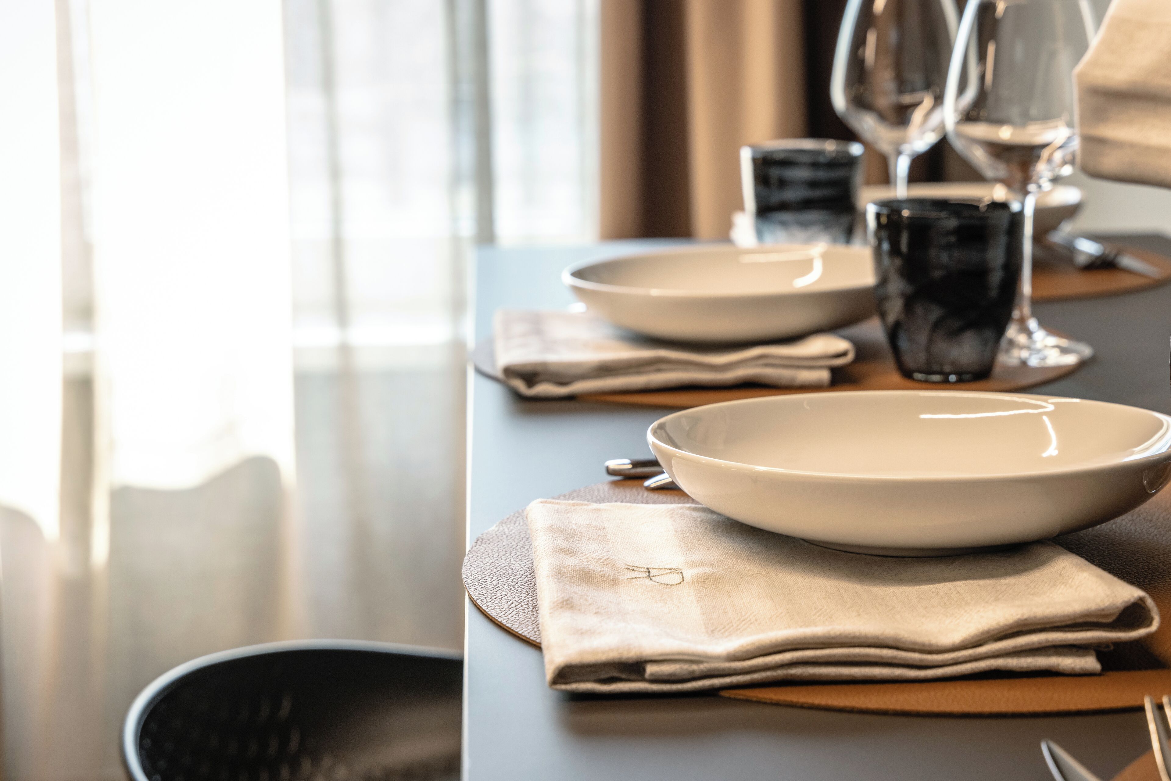 Een eettafel gedekt met borden, glazen en een servet.