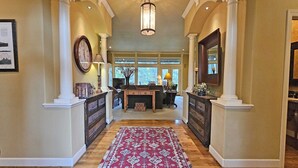 A spacious hallway with a wooden floor, a red patterned rug, and a large clock on the left. - 7 Titleist-Sunriver, Oregon: Woodlands Golf Course View, Air Conditioning, SHARC Aquatics, BBQ, WiFi, Mt. Bachelor, Deschutes River, Tennis, Bike Paths (Sunriver)
