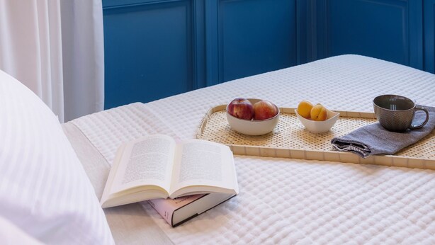 A bedroom with a bed, an open window with blue shutters, a tray with fruits and a cup, and a book on the bed. - Villa Plaka 3BR 9ppl Private Yard, 200m from Acropolis Metro&Museum (Athina)