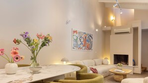 A modern living room with a white sofa, a round coffee table, and a dining table with a vase of flowers. - Villa Plaka 3BR 9ppl Private Yard, 200m from Acropolis Metro&Museum (Athina)