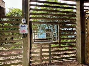 A wooden gate with a metal gate, a sign, and a view of a building through the gate.