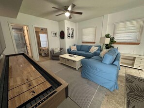 A living room with a pool table, blue sofa, and a ceiling fan.