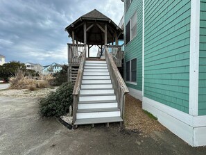 Una escalera de madera conduce a una zona techada con vistas a un edificio residencial.