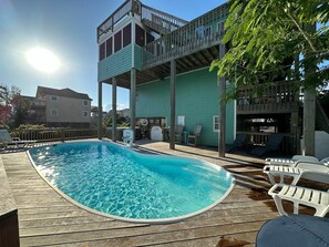 A swimming pool with a wooden deck, lounge chairs, and a building with a balcony. - 6BR ocean-side Corolla retreat with pool, hot tub, and beach access. CP-47 (Corolla)