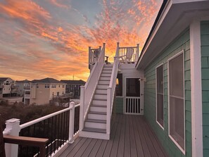 A wooden deck with a staircase leading to a covered area, surrounded by buildings.