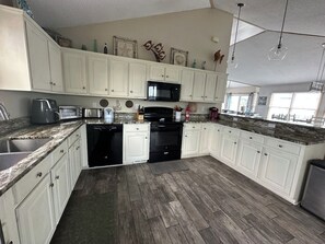 A kitchen with white cabinets, a microwave, a dishwasher, and a stove. - 6BR ocean-side Corolla retreat with pool, hot tub, and beach access. CP-47 (Corolla)