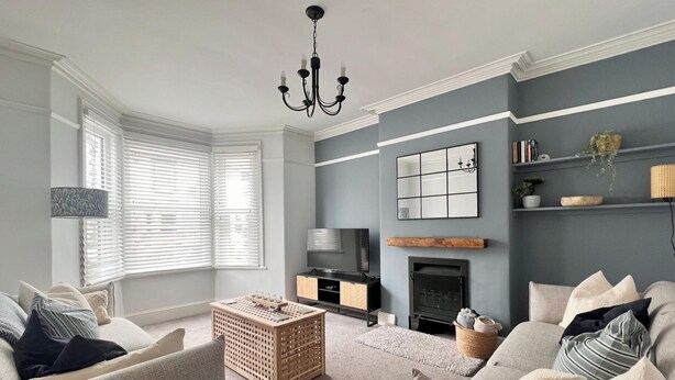 A living room with a fireplace, a TV, and a bookshelf. - Seaside Haven at Willowdene Cottage (Llandudno)