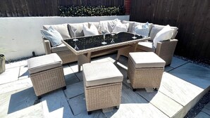 A wicker outdoor seating area with a glass-top table and cushioned chairs. - Seaside Haven at Willowdene Cottage (Llandudno)