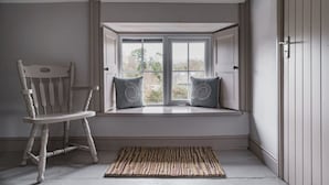 A room with a window seat, a rocking chair, and a patterned rug.
