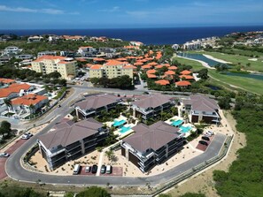Un complejo turístico costero con varias edificaciones, un campo de golf y una piscina.