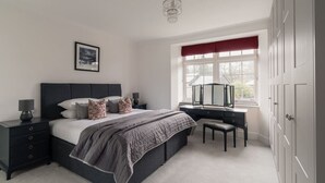 A bedroom with a bed, bedside table, dresser, and a window with a view.