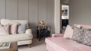 Een woonkamer met twee banken, een klein bijzettafeltje en een boekenkast op de achtergrond.