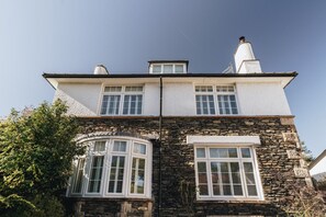 A two-story stone building with white trim and multiple windows, including a bay window. - Crossriggs- beautiful detached home (Cumbria)