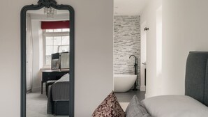 Een slaapkamer met een grote spiegel, een bureau en een badkuip.