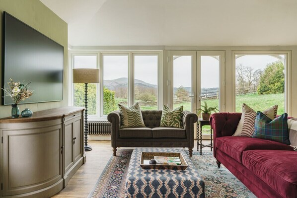 Relax in this inviting living room with a scenic view, featuring a sofa, ottoman, and flat-screen TV.