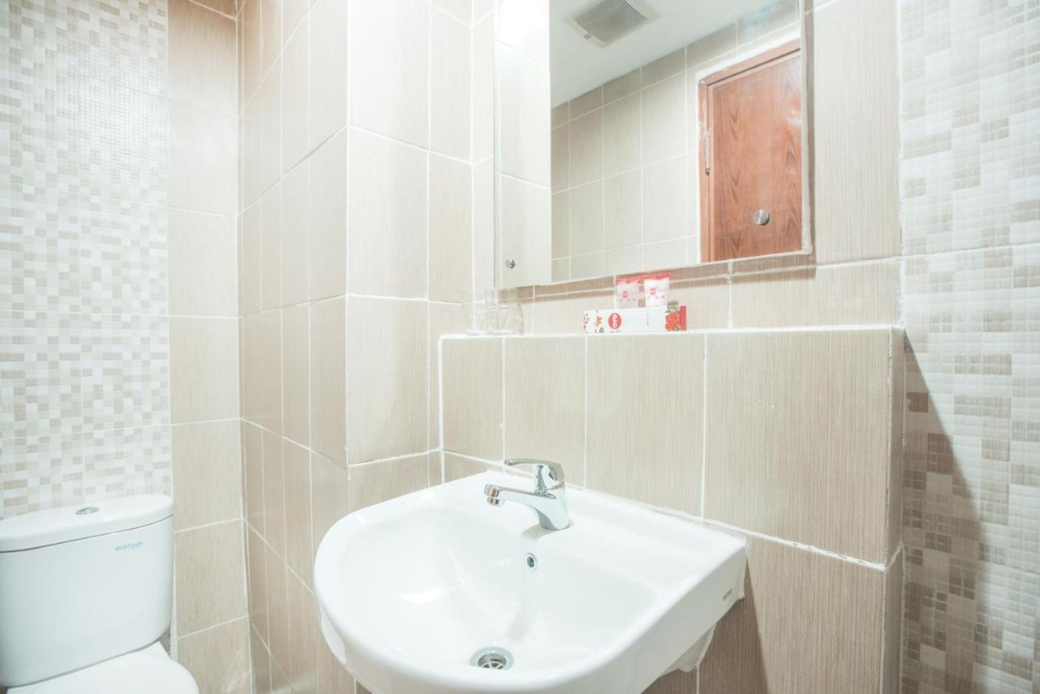 A bathroom with a white sink, a mirror, and a toilet.