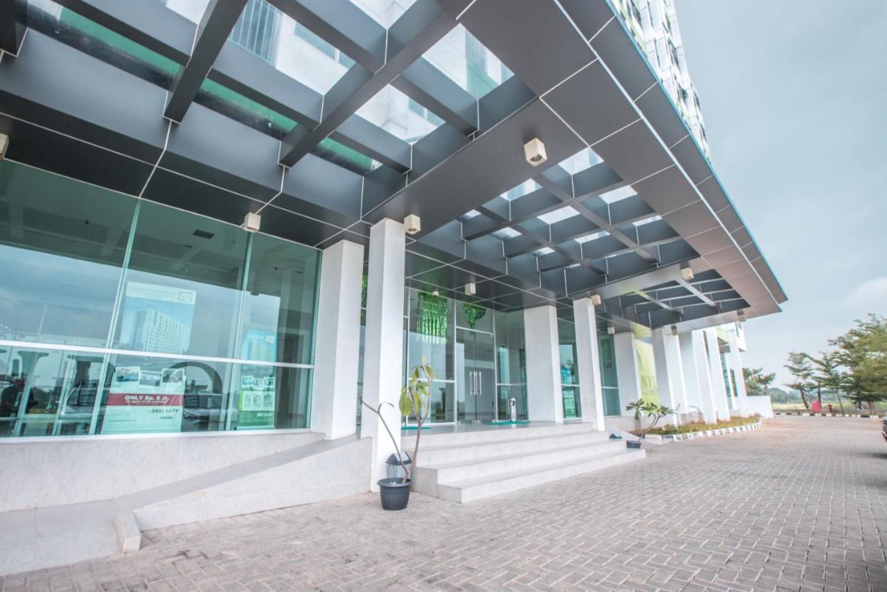 A modern building with large glass windows, a covered entrance, and a paved walkway.