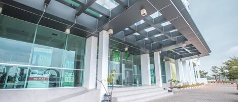 A modern building with large glass windows, a covered entrance, and a paved walkway.