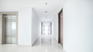 A long, narrow hallway with a shiny tiled floor and white walls.