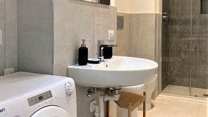 A modern bathroom with a built-in washing machine, a sink, and a shower. - Contemporary studio- Ornato 13 (Milan)