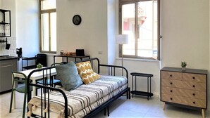 A compact living space with a sofa, a small table, a cabinet, and a window with a view of the outside. - Contemporary studio- Ornato 13 (Milan)