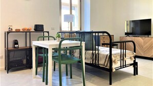 A compact room with a bed, a desk, a chair, a TV, and a window. - Contemporary studio- Ornato 13 (Milan)
