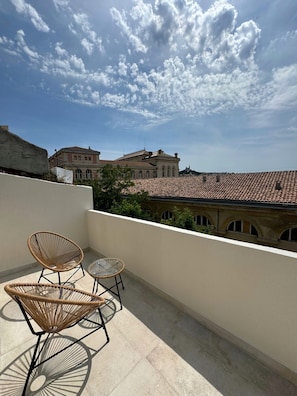 Relax on the rooftop with a clear view of the historic building, surrounded by wicker chairs and a small table.