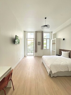 Relax in a serene bedroom with a large bed, desk, and balcony access.