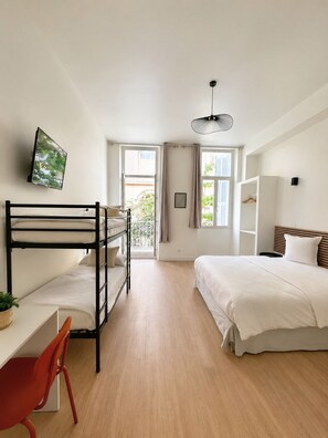 Una habitación con literas, un escritorio y una silla, una cama, un televisor y una ventana con vistas.
