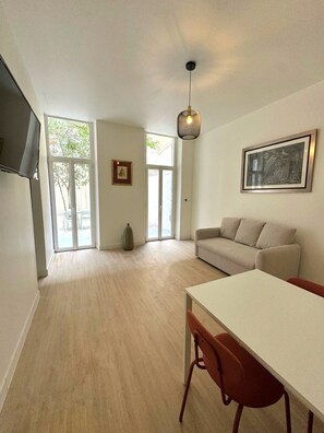 Relax in this stylish living space with a sofa, dining table, and large window.